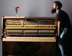 specialist carefully lifting a grand piano in preparation for relocation